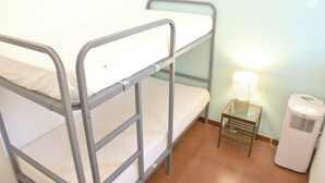 Una cama litera con una mesita pequeña y una lámpara a su lado.