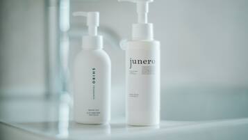 Two white bottles of Shiro and Junero body care products on a reflective surface.