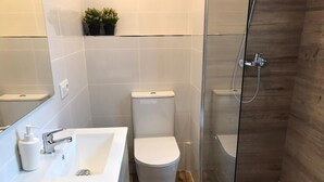 A modern bathroom with a glass-enclosed shower, a white sink with a soap dispenser, and a toilet. - Sweet BCN Studio with Terrace (Barcelona)