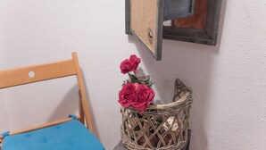 A wicker basket with flowers on a small table next to a chair with a blue cushion. - Sweet BCN Studio with Terrace (Barcelona)