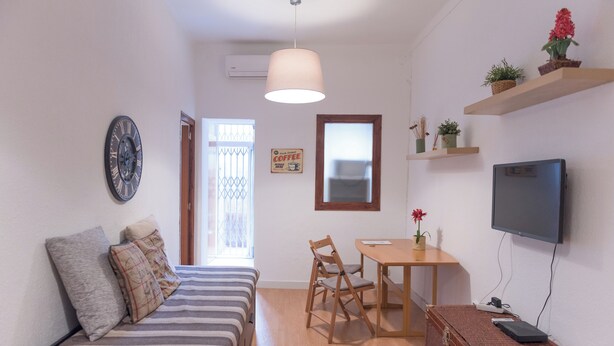 A compact living space with a bed, a dining table, a TV, and a small kitchenette area. - Sweet BCN Studio with Terrace (Barcelona)