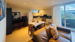 Un espacio habitable compacto con kitchenette, comedor y sofá con vistas al exterior.