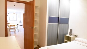 A bedroom with a bed, a wardrobe, and a desk area with a chair and table. - Sweet BCN Plaza Universidad (Barcelona)