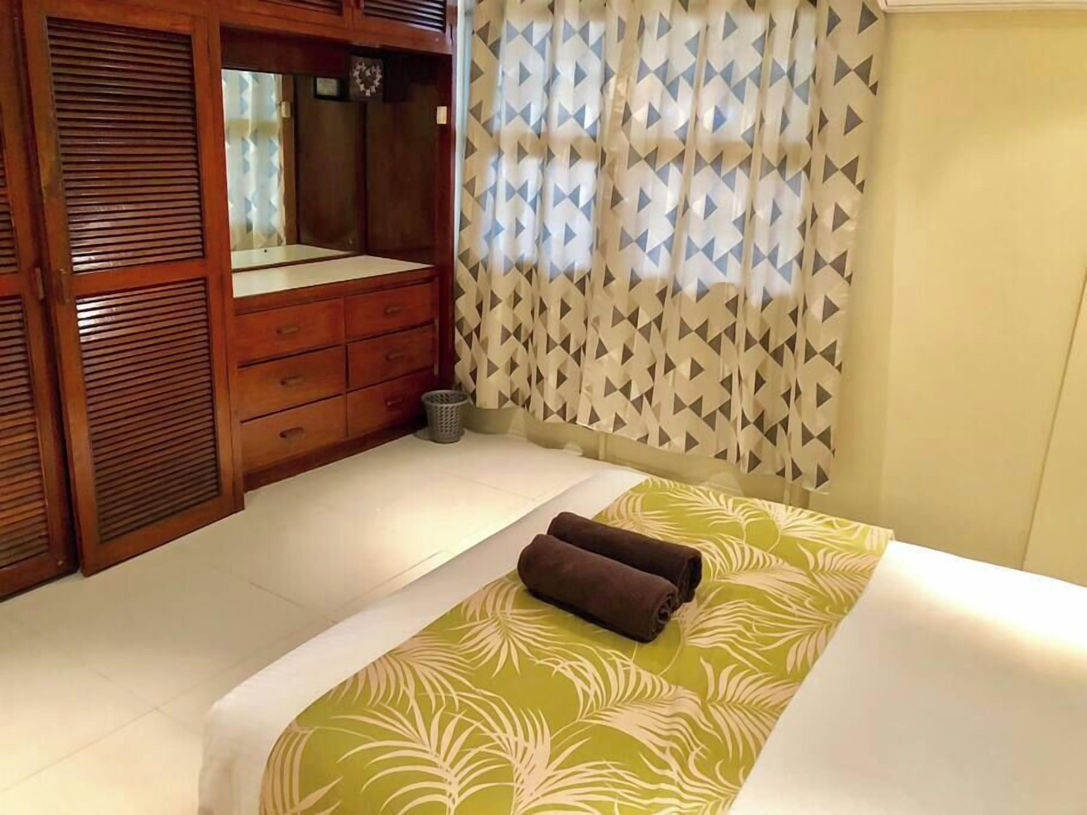 Una camera da letto con un letto, un'armadio in legno e una finestra con tende a motivi.