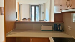 A compact kitchen with a built-in oven, a coffee maker, and a toaster on the counter. - Sweet BCN Rambla 48. (Barcelona)