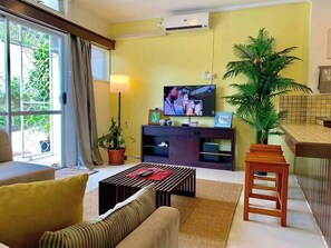 Una sala de estar con un sofá, una mesa de centro, un televisor y una planta en maceta.