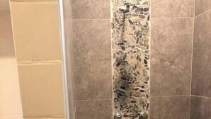 A bathroom with a shower area, a toilet, and a wall with a decorative tile pattern.
