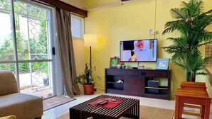 A living room with a sofa, a coffee table, a TV, and a potted plant.