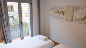 Ein Hotelzimmer mit einem Bett, einem Balkon und drei an der Wand befestigten Kunstwerken.
