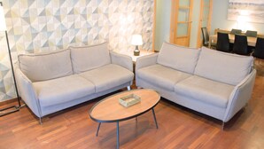Ein Wohnzimmer mit zwei Sofas, einem Couchtisch, einer Lampe und einem Essbereich mit Stühlen und einem Tisch.