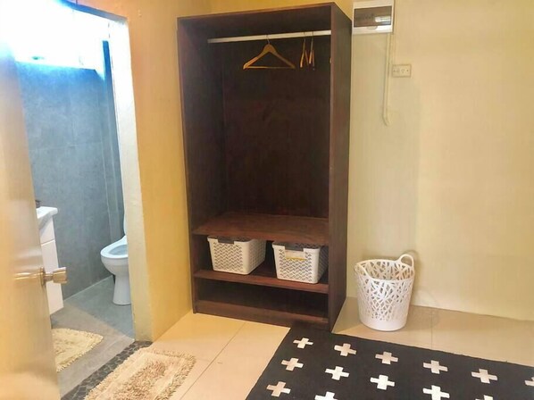 Une salle de bain avec un meuble en bois foncé, un panier blanc et un tapis à motifs.