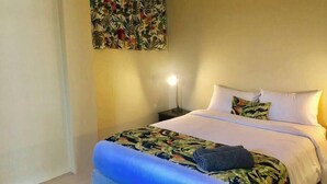 A hotel room with a bed, a nightstand, a wall tapestry, and a small rug.