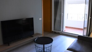 Un soggiorno con una televisione a schermo piatto, un tavolo rotondo e un divano.