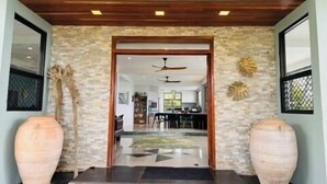 A modern entrance with a stone facade, a wooden ceiling, and two large vases.