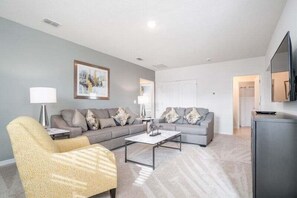 A living room with a sofa, armchair, coffee table, and a television.