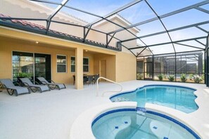 Una piscina interior con techo de cristal, sillones de descanso y una terraza con sol.