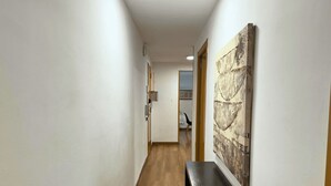 A hallway with a wooden floor, a black bench, and a large abstract painting on the wall.