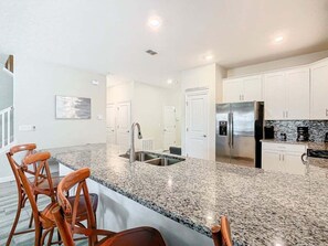 Una cocina moderna con encimeras de granito, electrodomésticos de acero inoxidable y armarios blancos.