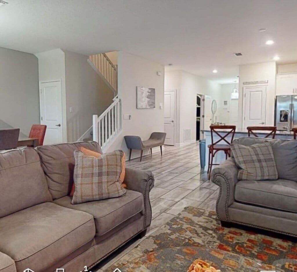 A living room with two sofas, a patterned rug, and a staircase.