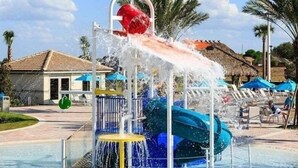 Um parque aquático com um tobogã, piscina e espreguiçadeiras.
