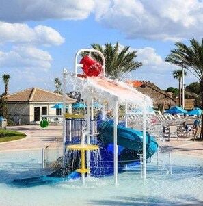 Un parco acquatico con uno scivolo, una piscina e lettini.