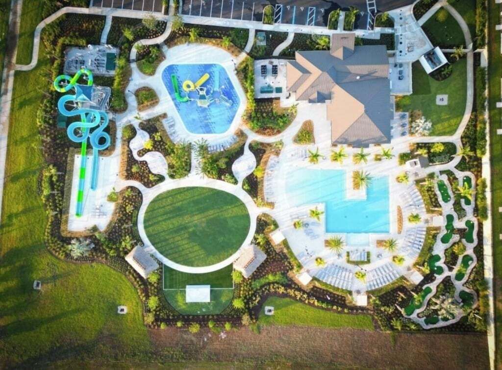 An aerial view of a resort with multiple swimming pools, a water slide, and landscaped areas.