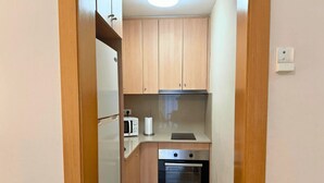 A compact kitchen with wooden cabinets, a microwave, a toaster, and an oven. - 2 BEDROOM DUPLEX (Barcelona)