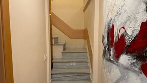 A staircase with a wooden handrail and a wall with abstract art. - 2 BEDROOM DUPLEX (Barcelona)