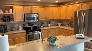 A modern kitchen with wooden cabinets, stainless steel appliances, and a central island. - Luxury Penthouse Bella Lago 441 (Fort Myers Beach)