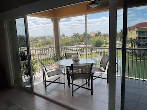 Un balcon avec une table et des chaises, une vue sur un paysage verdoyant et un bâtiment en arrière-plan.