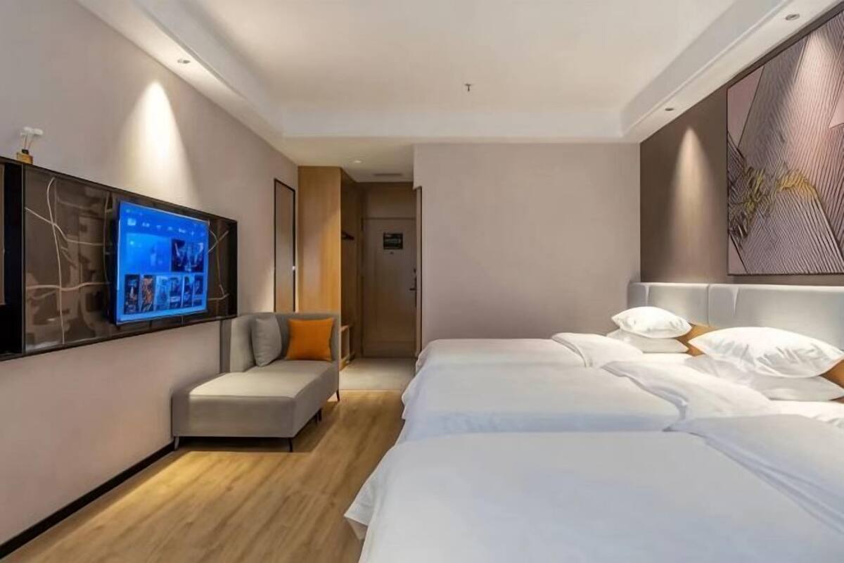 Une chambre d’hôtel équipée d’un lit, d’une télévision, d’un canapé et d’une œuvre d’art accrochée au mur.