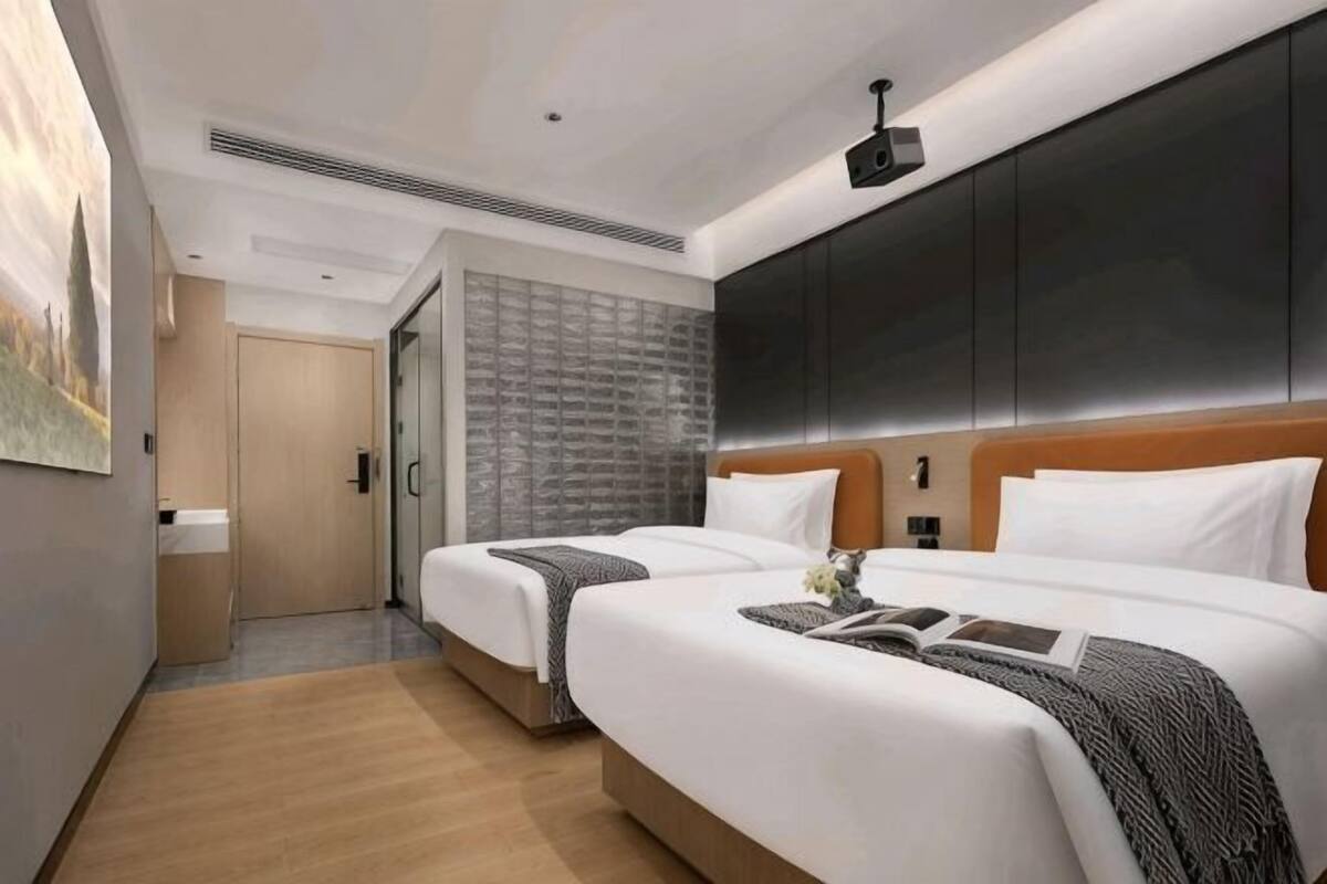 Une chambre d’hôtel avec deux lits, un grand téléviseur fixé au mur et une porte donnant sur la salle de bain.