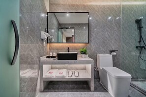 Een moderne badkamer met een marmeren wastafel, een grote spiegel, een toilet en een douchehoek.