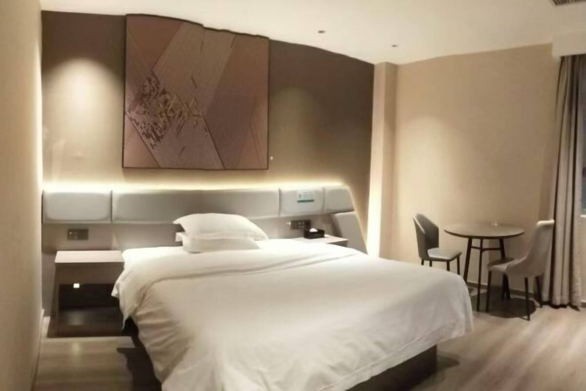 Une chambre d’hôtel moderne avec un grand lit, un bureau et une petite table.