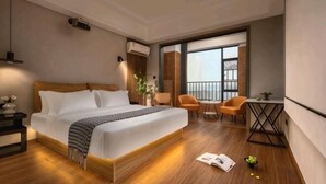 Ein modernes Hotelzimmer mit einem großen Bett, einem kleinen Tisch, einem Sessel und einem Balkon mit Blick.
