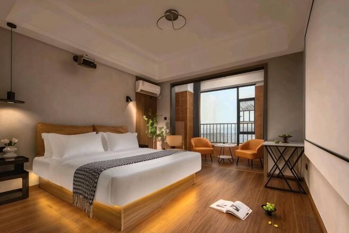 Une chambre d’hôtel moderne avec un grand lit, une petite table, une chaise et un balcon avec vue.