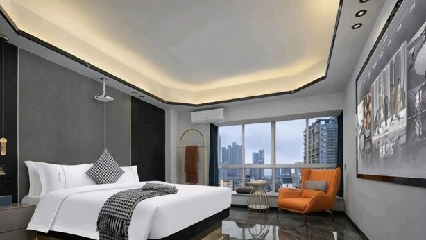 Ein modernes Hotelzimmer mit einem großen Bett, einer Sitzecke und Blick auf die Stadt.
