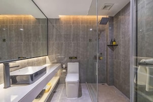 A modern bathroom with a glass shower enclosure, a white toilet, and a vanity with a mirror.