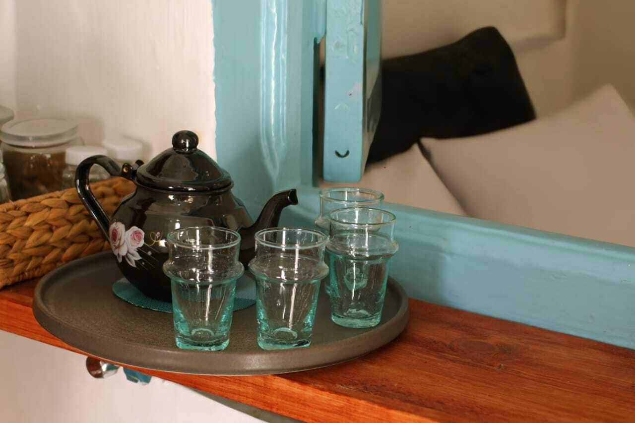 A tray with a teapot and four glasses on a wooden surface.