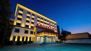 A modern hotel with a prominent entrance, multiple floors, and a well-lit facade. - Qixian Hotel (Qi County)