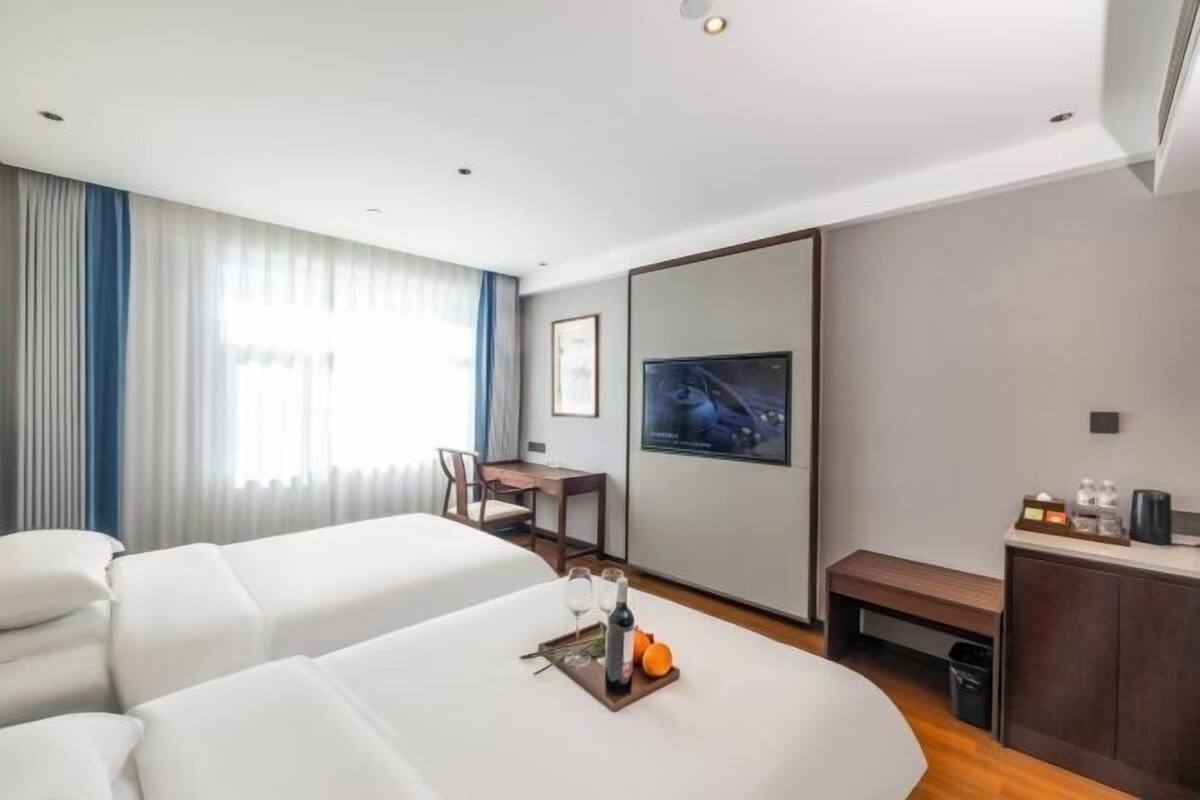 Habitación de hotel con dos camas, un escritorio, un televisor y un banco.