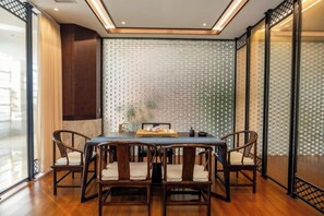A dining area with a wooden table and chairs, a patterned wall, and a view through a glass partition. - Qixian Hotel (Qi County)