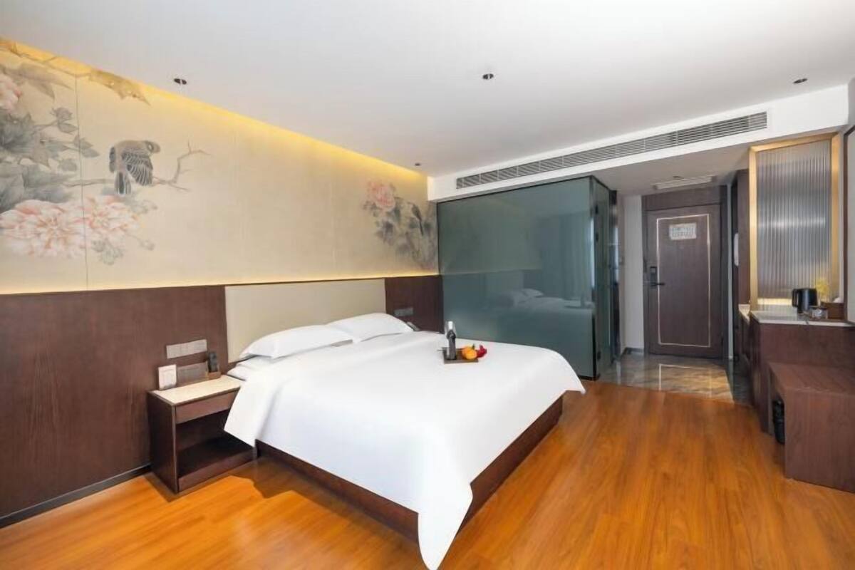 Una habitación de hotel con cama, mesita de noche y una pared decorada con obras de arte.