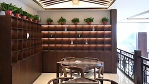 A modern interior with a wooden wall unit displaying potted plants, a glass table with chairs, and a ceiling with wooden slats. - Qixian Hotel (Qi County)