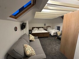 Un dormitorio con una cama grande, un sofá y un tragaluz.