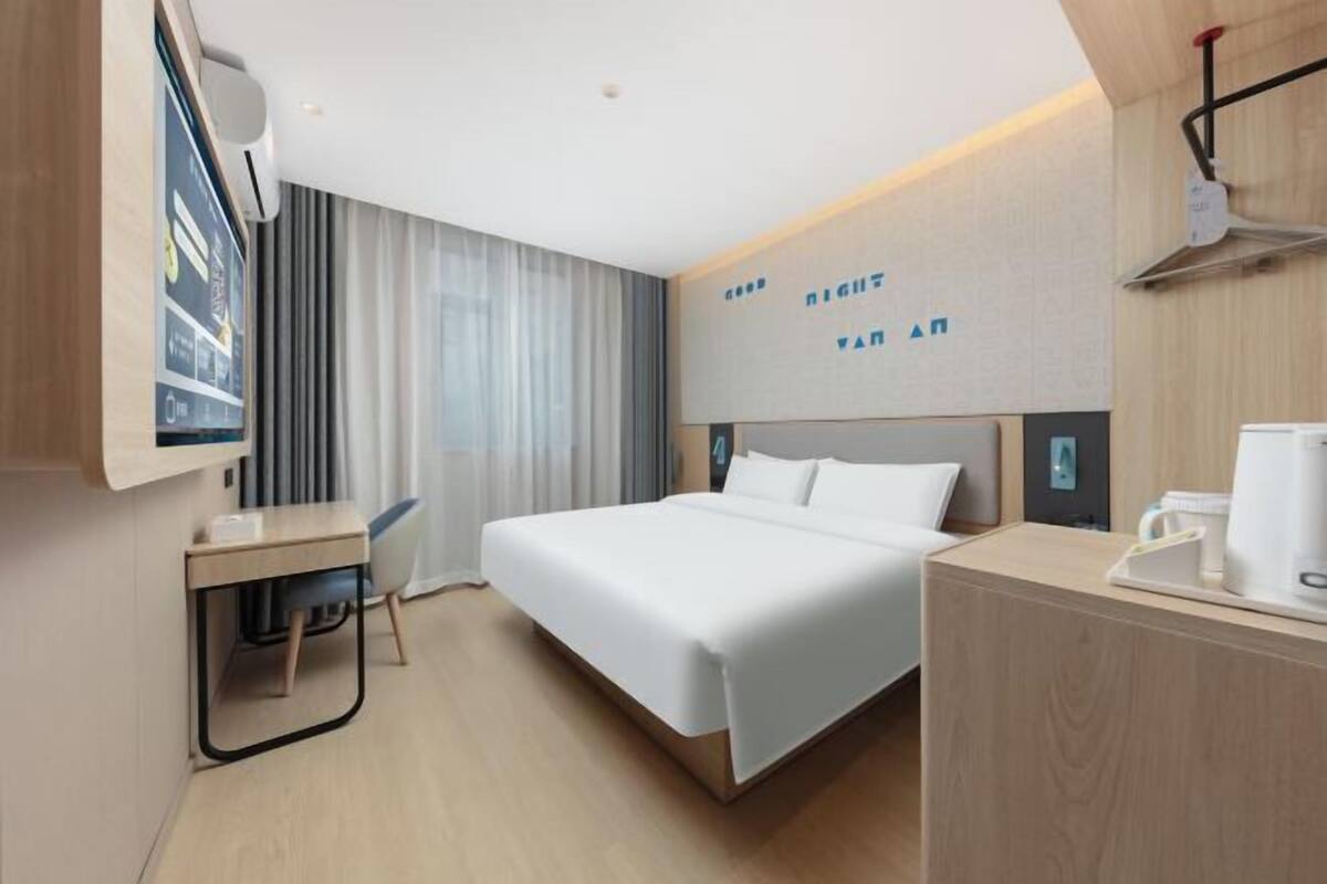 A modern hotel room with a bed, a desk, and a coffee machine.
