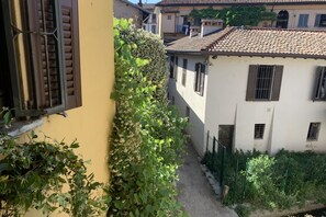 Une ruelle étroite entre deux bâtiments, avec un mur jaune sur le côté gauche et un bâtiment blanc sur le côté droit.