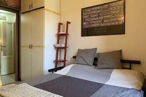 Une chambre à coucher avec un lit, des oreillers, une échelle, une armoire et un tableau encadré au mur.