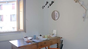 Um quarto com escrivaninha de madeira, uma cadeira, uma janela e uma parede com uma frase motivacional.