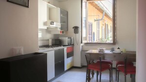 Uma cozinha compacta com área de refeições, uma janela com vista e um telefone na parede.